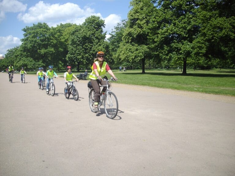 Children cycling with an instructor in a London park, on a shared-use path