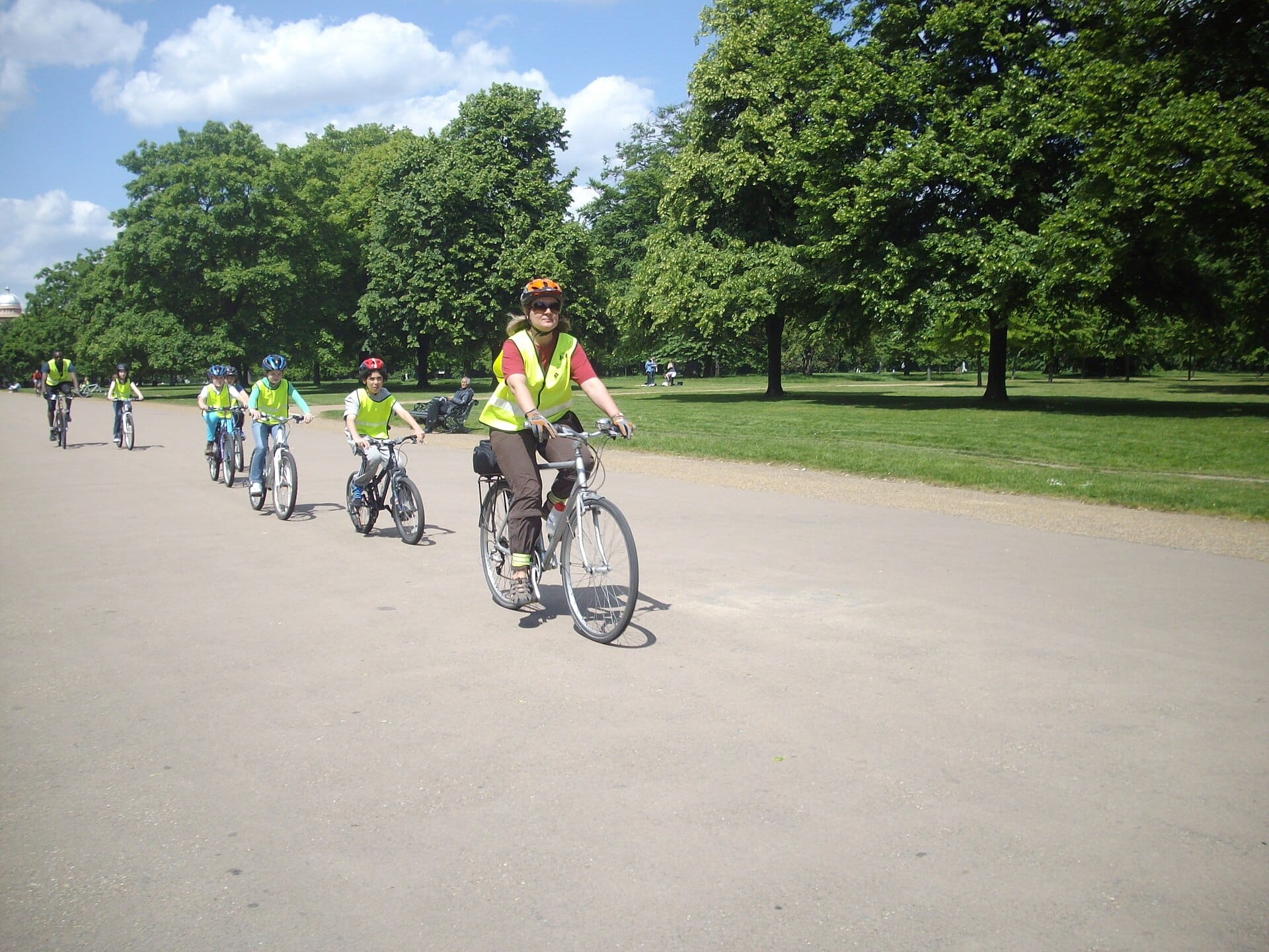 Children cycling with an instructor in a London park, on a shared-use path