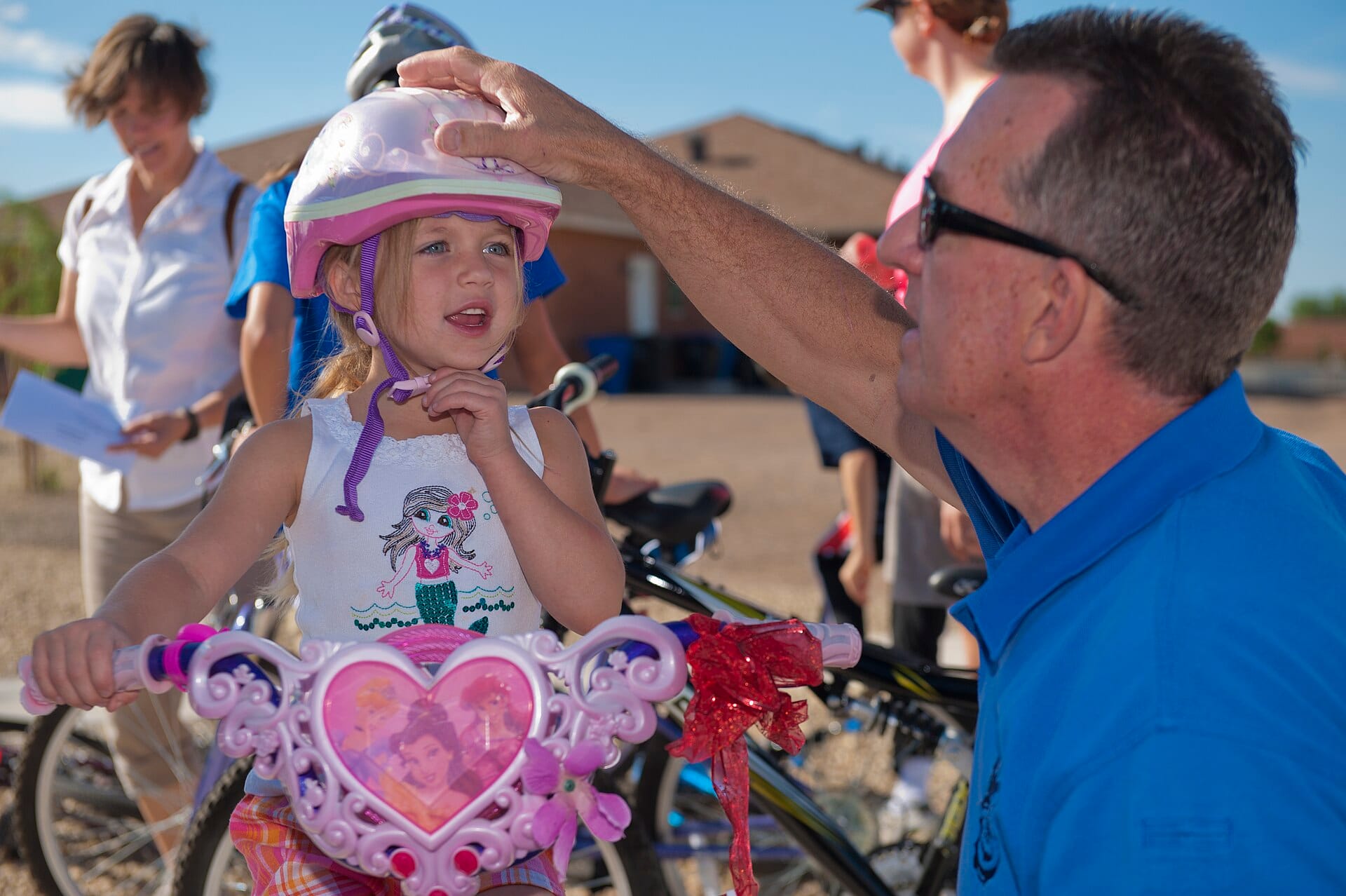 Adult adjusting a child's bike helmet before a ride